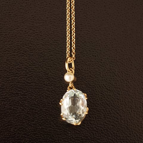 A necklace of 14k gold set with a aquamarine and a pearl