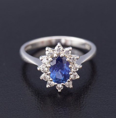 A ring set with a sapphire and wreathed with diamonds, in total 0,36 ct. mounted 
in 18 kt. white gold