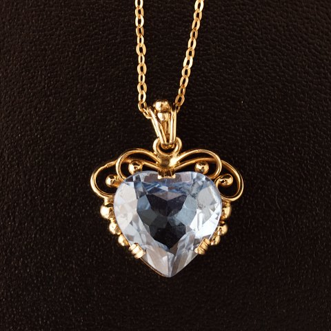 A necklace of 14k gold, set with a blue topaz pendant, shaped as a heart with 8k 
gold chain