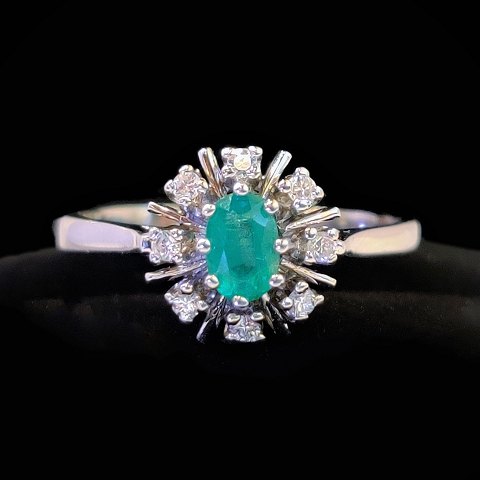 An emerald ring with diamonds mounted in 14k white gold